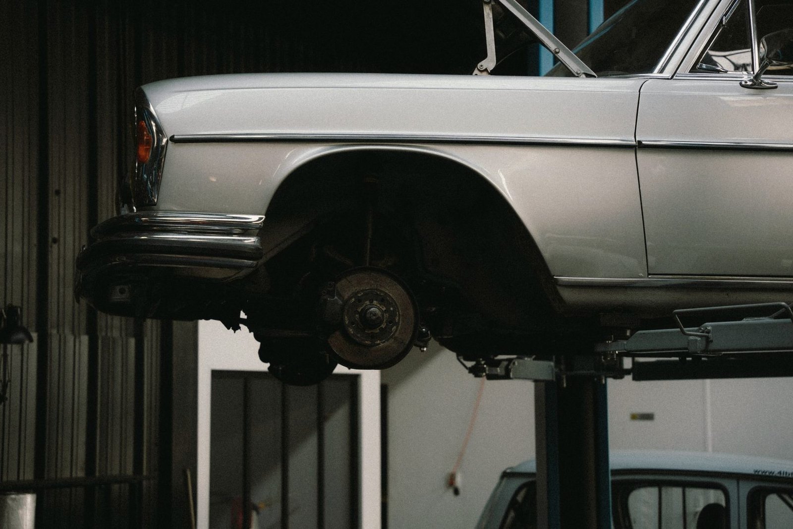 An older sedan raised on a two-post lift