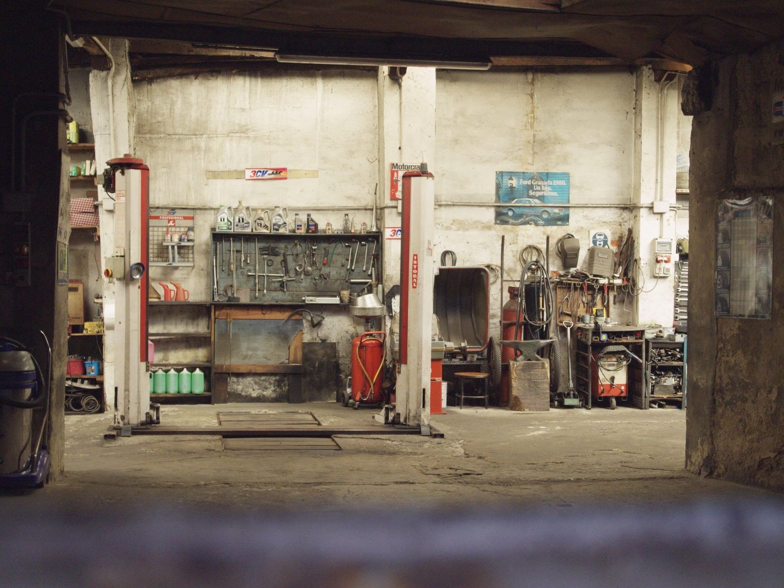 An empty repair bay with two lifts and a tool wall