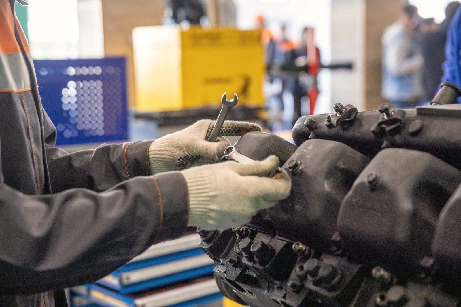 Gloved hands working a wrench on a transmission housing