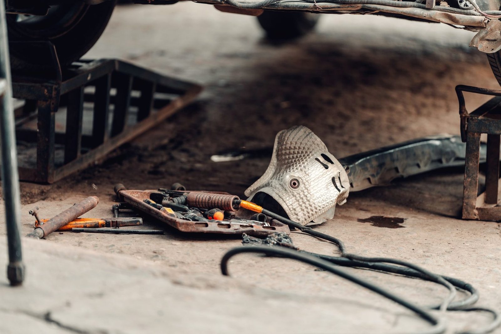 Hand tools on a shop floor under a raised car